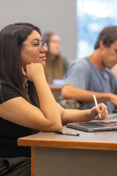 a nursing student takes notes on a tablet in a lecture