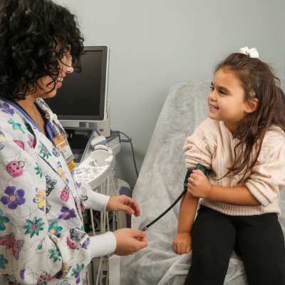 a clinical research coordinator checks a child participant's blood pressure