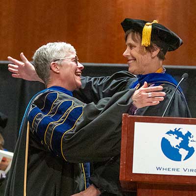 jo robins hugs dean jean giddens at a graduation ceremony