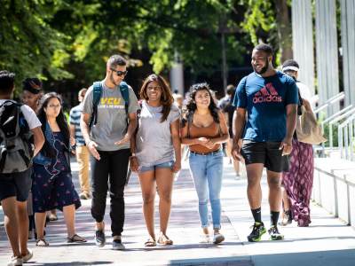 four v.c.u. students walk on monroe park campus in front of the cabell library