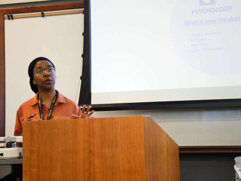 a professor delivering a lecture from a lectern in a classroom