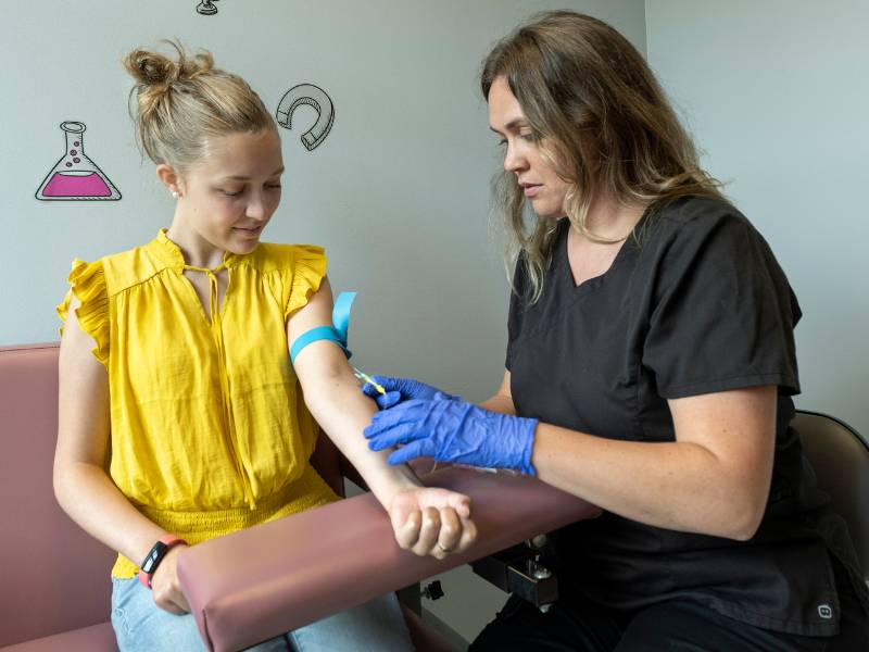 A nurse researcher draws blood from a study participant