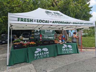 two people set up the shalom farms market stand