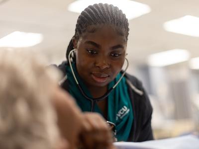 a nursing student listening to a patient heartbeat with a stethoscope