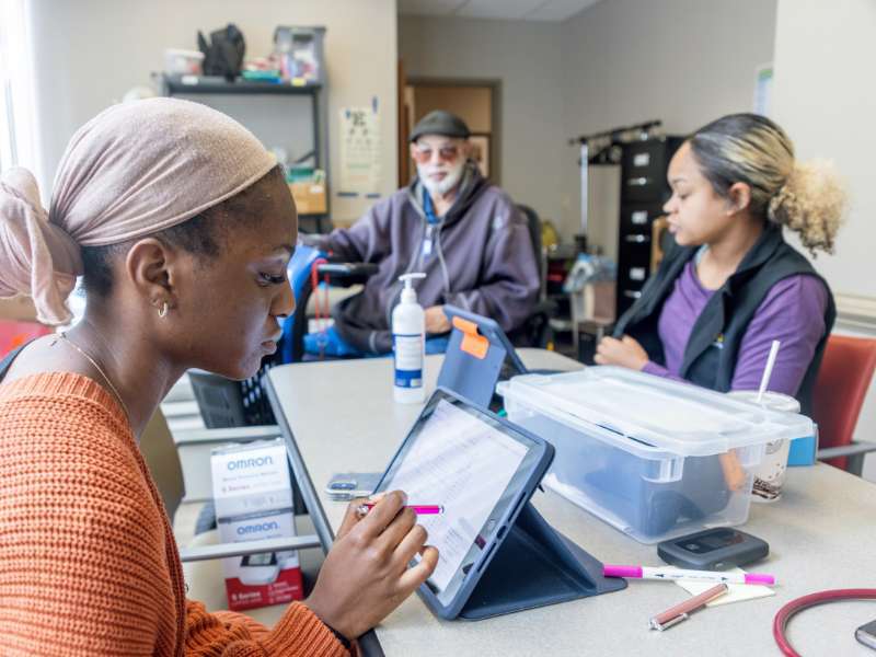 a v.c.u. nursing student consults a tablet computer while serving in a community health clinic