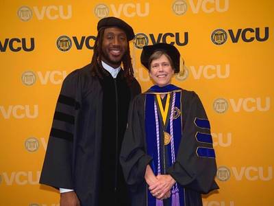 alumnus mo alie cox poses for a graduation photo with jean giddens