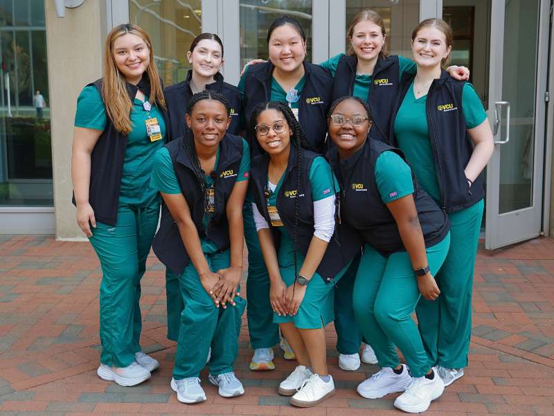 a group of v.c.u. nursing students poses for a group photo in front of the school after the vesting ceremony