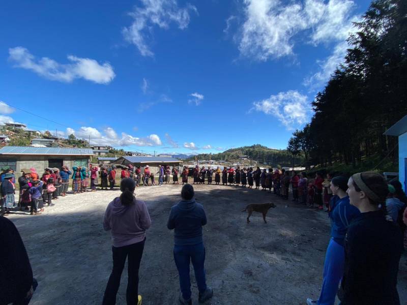 a large group of guatamalans and v.c.u. nursing students and professors stands outdoors in a large circle with a dog in the middle