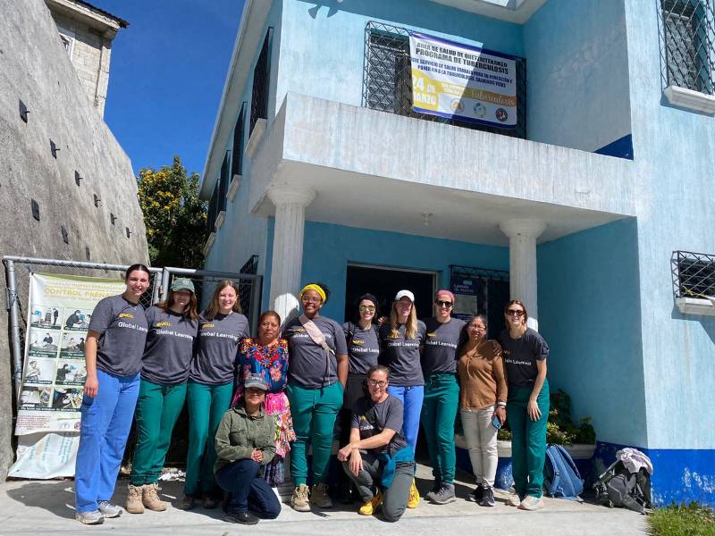 a group of nine v.c.u. nursing students and three local health care workers posing in front of a health clinic in guatemala