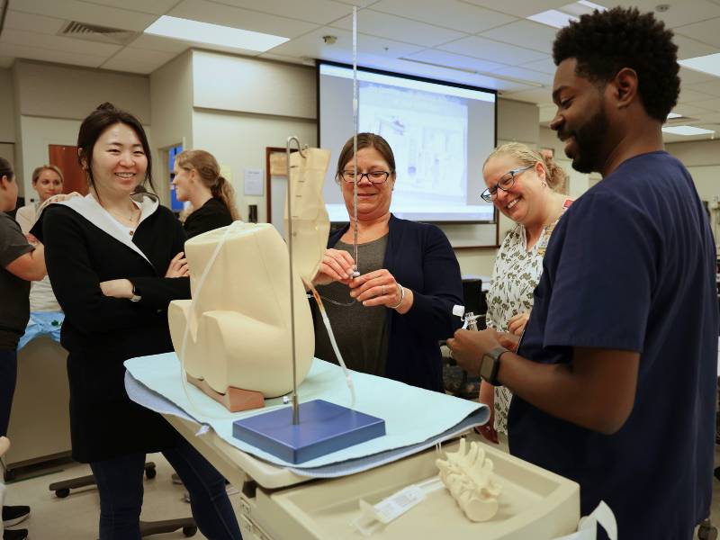 a group of d.n.p. students work with a faculty member in the clinical learning center