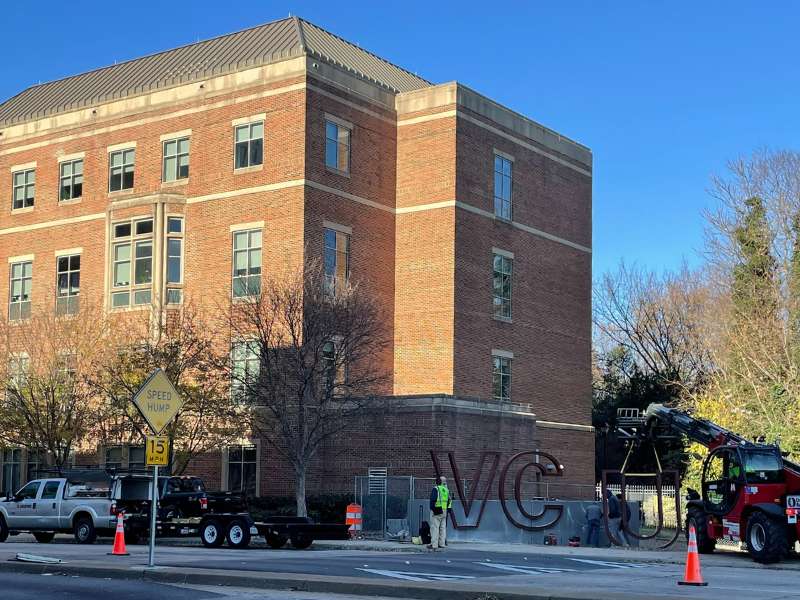 a construction crew lifts the letter 'u' into the new v.c.u. letters outside of the school of nursing building