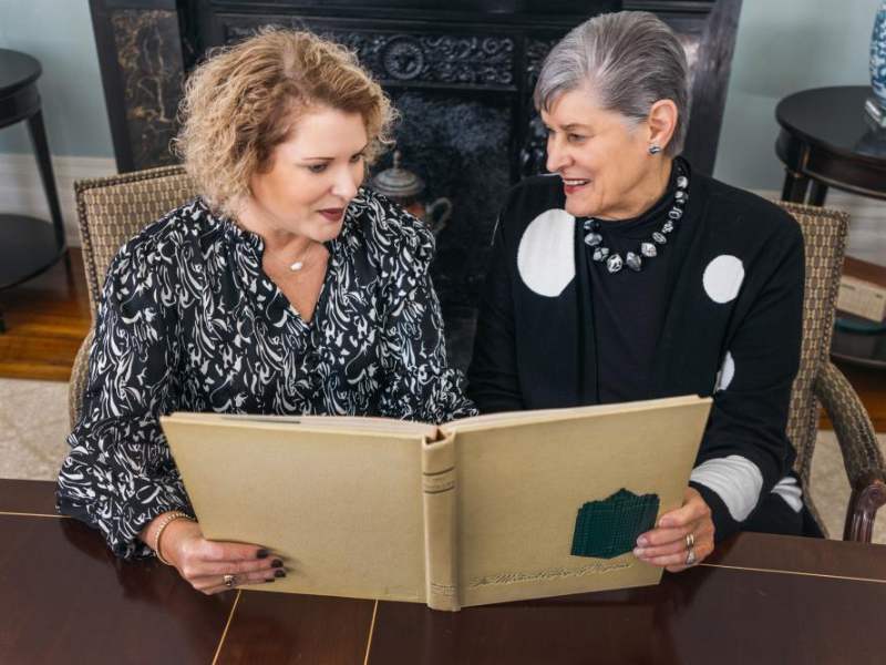 michelle edmonds and judy collins look at betsy bampton's yearbook together