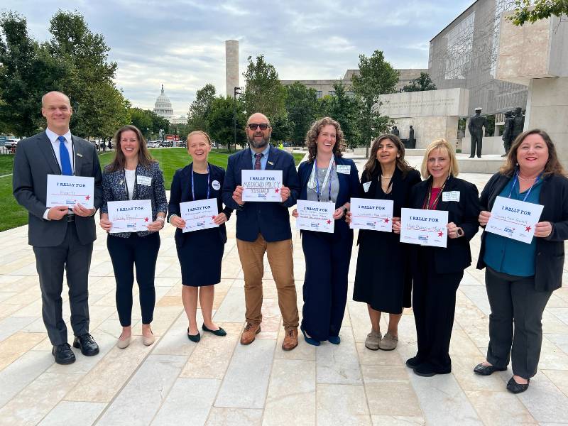 a group of v.c.u. health sciences faculty stand in front of the u.s. capitol with rally signs