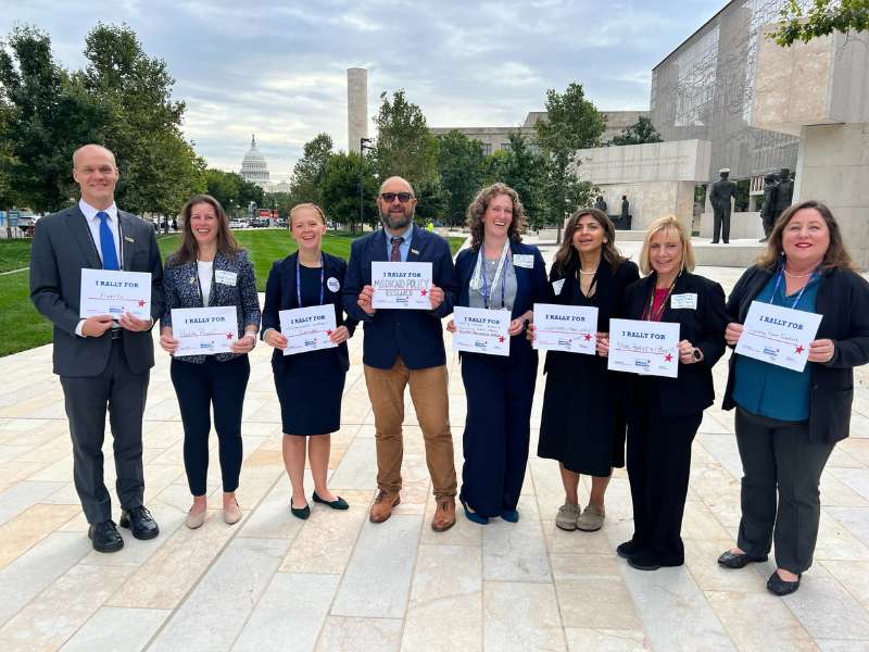 a group of eight v.c.u. health sciences faculty hold rally signs with the u.s. capitol in the background