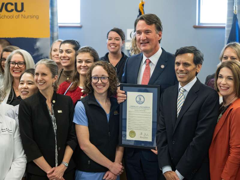 a group of v.c.u. nurse practitioners, school leadership, president rao gather around governor glen youngkin who holds a framed copy of the nurse practitioners week proclamation