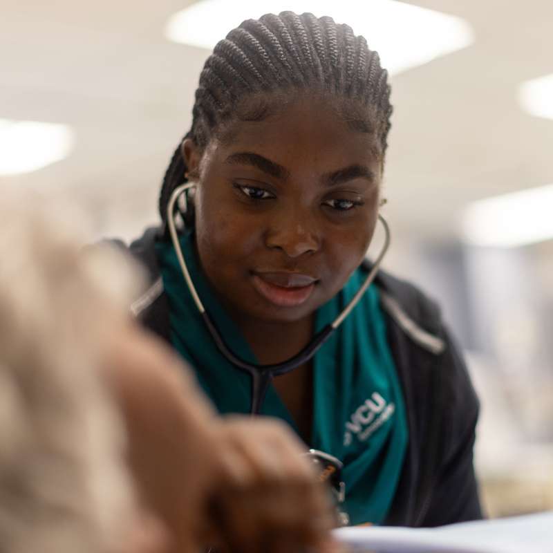 a nursing student listening to a patient heartbeat with a stethoscope