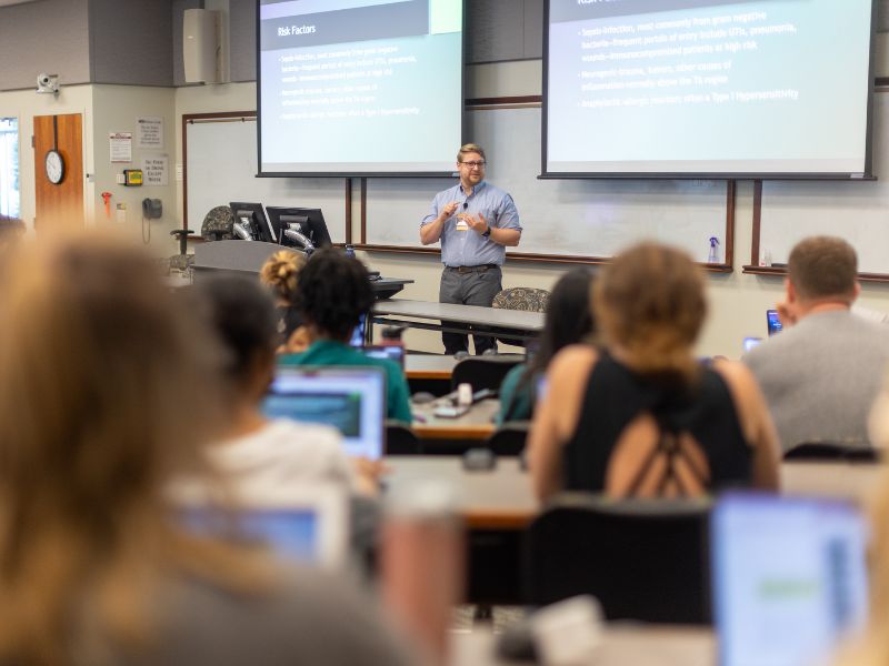 A professor lectures a room of nursing students