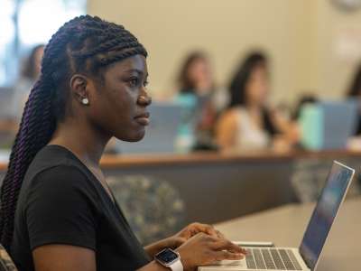 an undergrad student takes notes on a laptop in a lecture