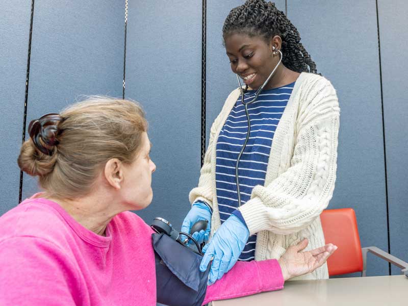 a health practitioner smiles while taking a patient's blood pressure