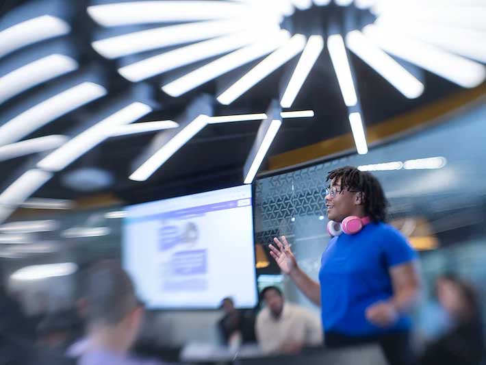 a student gives an energetic presentation to a light-filled classroom