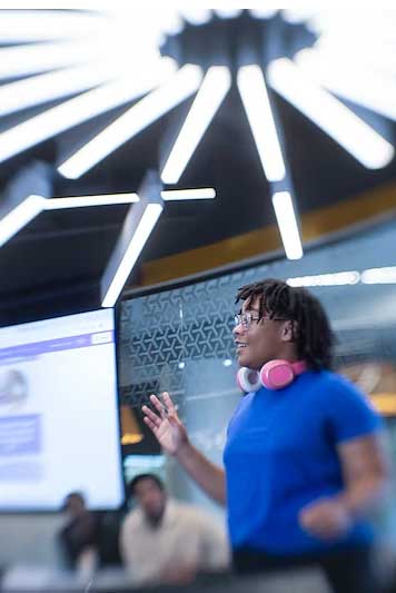 a student gives an energetic presentation to a light-filled classroom